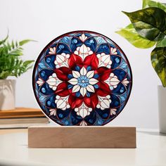 a colorful glass plate sitting on top of a wooden stand next to a potted plant