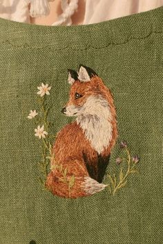 a close up of a pillow with a fox on it's side and flowers in the middle