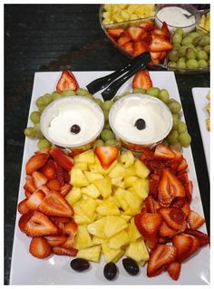 a plate topped with fruit and an owl face made out of grapes, strawberries