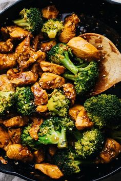 chicken and broccoli stir frying in a skillet with a wooden spoon