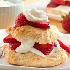 strawberry shortcakes stacked on top of each other with whipped cream and strawberries