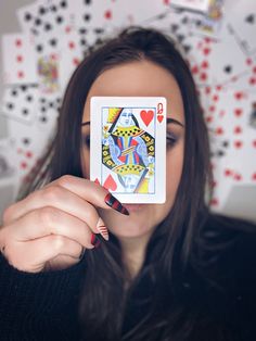 a woman holding up a playing card in front of her face