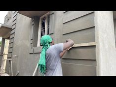 a man is painting the side of a building with green scarfs on his head