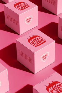 several pink boxes with red and white designs are arranged on a bright pink surface,