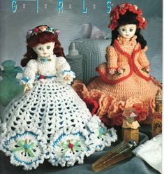 two crocheted dolls sitting next to each other on the cover of a book