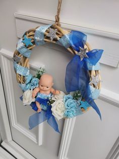 a baby's first christmas wreath hanging on the front door with blue flowers and stars