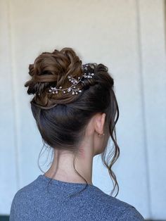 a woman with her hair in a low bun wearing a flowered headpiece, looking off to the side