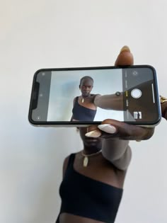 a woman holding up her cell phone to take a selfie with another person's hand