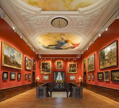 an empty room with paintings on the walls and ceiling painted red, white and gold