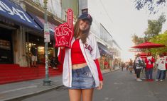 a girl is standing on the street holding up a peace sign