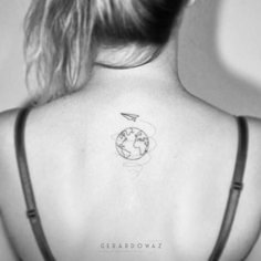 the back of a woman's neck with a small earth tattoo on her left shoulder