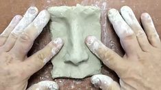 two hands that are making some kind of face out of clay on a table with flour all over it