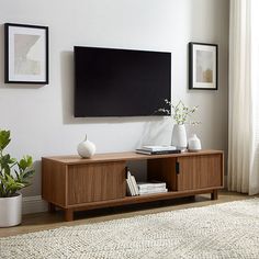 a living room with a large flat screen tv mounted on the wall above a wooden entertainment center