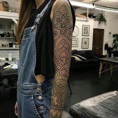 a woman with a tattoo on her arm standing in front of a table and chair