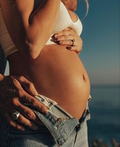 a man and woman standing next to each other with their hands on their stomachs