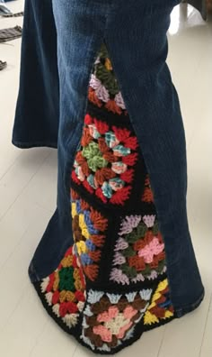 a person standing on the floor wearing jeans and a crocheted skirt with pockets