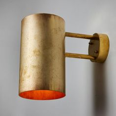 a gold colored wall light with an orange shade