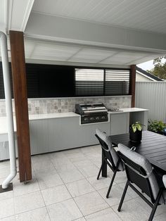 an outdoor kitchen and dining area is shown in this image, with black chairs around the table