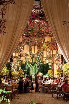 an outdoor dining area with lots of tables and chairs, lit up by hanging lanterns