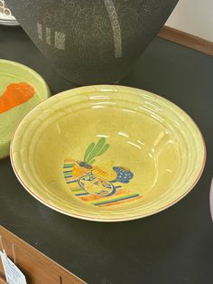 two bowls with designs on them sitting on a table next to a vase and other items