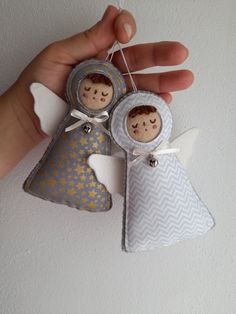 an angel ornament being held by someone's hand with another angel hanging from it