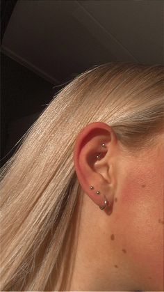 a woman with long blonde hair wearing a pair of ear piercings on her ears