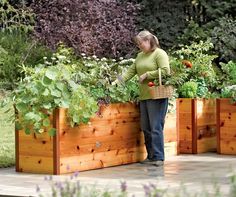 a woman standing next to two wooden planters filled with plants