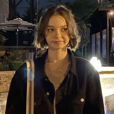 a woman standing in front of a fountain at night with her hand on her hip