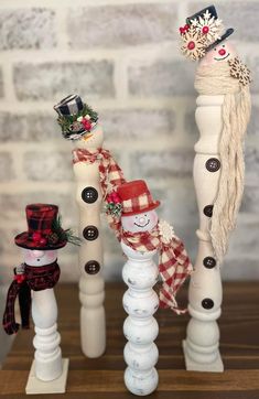 three snowmen are standing next to each other on top of wooden poles, decorated with red and white decorations