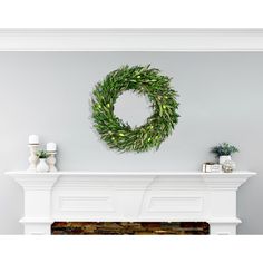 a white fireplace with a wreath on the mantle