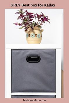 the grey box for kallax is next to a potted plant on top of it