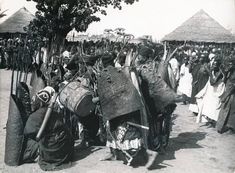 an old black and white photo of people in native garb walking down a dirt road