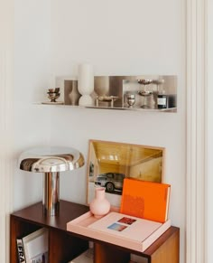 a table with books and vases on it in front of a wall mounted shelf