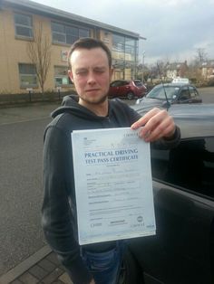 a man holding up a certificate in front of a car