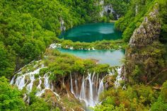 the plit is surrounded by green trees and blue water, with waterfalls in the foreground