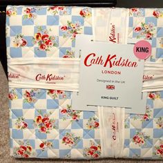 a blue and white quilted bag with red flowers on it, sitting on the floor