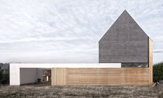 the house is made out of wood and has a sloping roof that extends into an open field