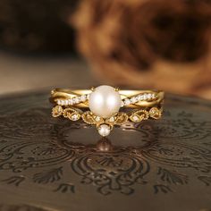 a close up of a ring with pearls and diamonds on it's side, sitting on a table