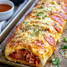 a close up of a pizza roll on a tray with sauce and pepperoni in the background