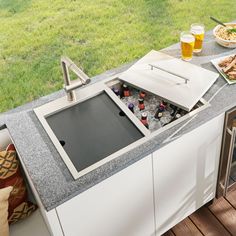 a kitchen sink sitting on top of a counter next to a plate of food and drinks