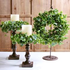 three candles are placed on top of each other with greenery in the shape of a wreath