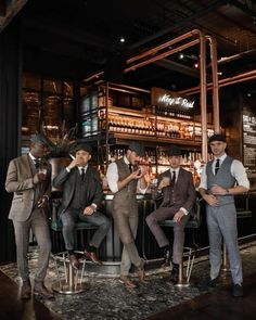 four men in suits are sitting at a bar