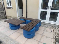 a wooden bench sitting on top of a stone floor next to blue barrels and windows