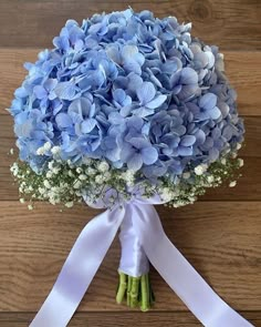 a bouquet of blue hydrangeas and baby's breath tied to a white ribbon