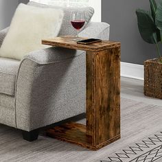 a living room with a couch, chair and wine glass on the end table in front of it