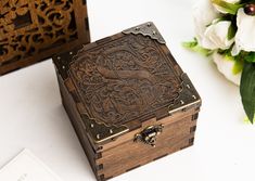 an ornate wooden box sitting on top of a table next to flowers and a card holder