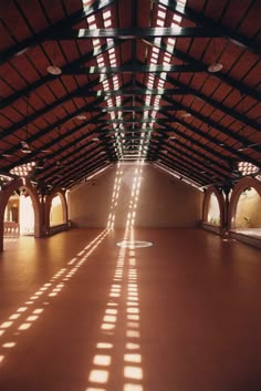 the sun is shining through the windows in an empty room with arches and beams on the ceiling