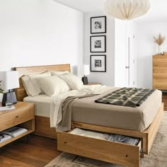 a bed sitting in a bedroom next to a wooden dresser under a white light fixture