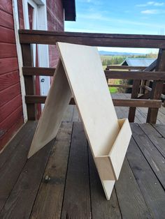 an upside down wooden object sitting on top of a wooden deck next to a red building