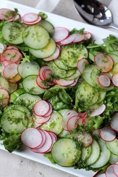 a white platter filled with cucumbers and radishes